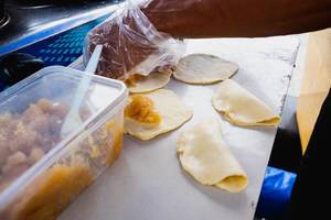 Empanadas werden vom Straßenhändler auf kleinem Tisch gefüllt