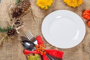 Empty plate with Cutlery on burlap with autumn background