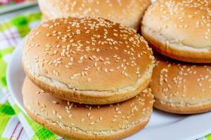 Empty sesame burger buns stacked on a plate