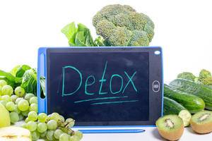 Entschlackung: Detox auf einer Tafel geschrieben, umgeben von grünen Lebensmitteln, Trauben, Gemüse und Salat