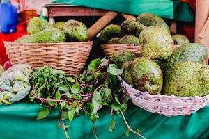 Exotisches Obst und Gemüse in Holzkörben verkauft von einem Straßenhändler