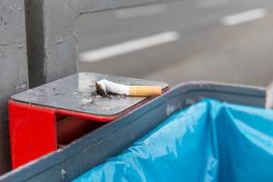 Expressed Marlboro cigarette spring lies on metal holder of a trash bin