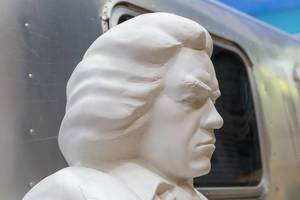 Face of white Beethoven statue in honor of the Beethoven Year 2020, in front of an old camping van