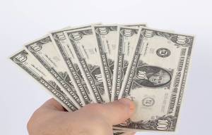 Fächer aus US-Dollar Banknoten gehalten von Hand vor weißem Hintergrund