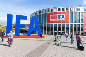 Fair visitors and e-scooters in front of the IFA Logo & consumer electronics und home appliances exhibition hall in Berlin, Germany