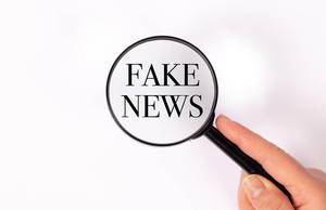 Fake news  unter der Lupe auf weißem Hintergrund