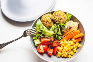 Falafel, hummus and vegetables buddha bowl with plate and fork
