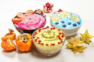 Farbenfrohes Frühstück: Haferflocken mit frischen Früchten, Beeren, Samen und gefärbter Creme