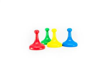 Farbige Spielfiguren in rot, grün, gelb und blau vor weißem Hintergrund