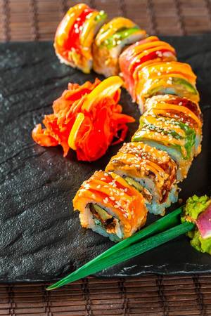 Farbiges, appetitlich angerichtetes Sushi mit Lachs auf schwarzer Steinplatte