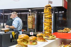 Fast-food - unterschiedliche Burger, ein Riesen Burgerturm und ein Dönerspieß im Hintergrund