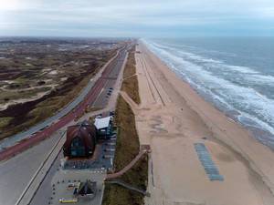 Fast menschenleerer Strand in den Niederlanden mit Küstenstraße und grünem Hinterland