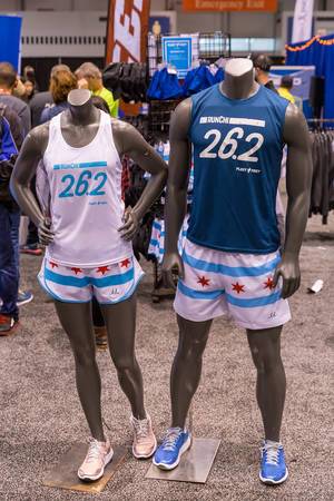 Female and male mannequin wearing Chicago Marathon outfit: tank top with "26.2" front print, white-blue shorts with four red stars and running shoes