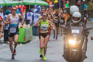 Female athlete nutrition intake at Frankfurt Marathon surrounded by male athletes