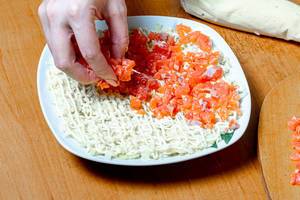 Female hand adds sliced salmon to salad