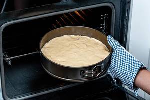 Female hand puts a baking tray with dough in the oven