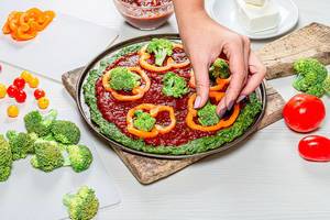 Female hands put pieces of broccoli on pizza. The concept of healthy food (Flip 2019)