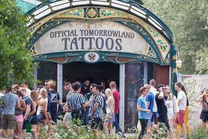 Festival people gather in front of the Official Tomorrowland Tattoos stage