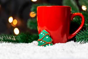 Festive background with a Cup of Tea and gingerbread tree on a snow background