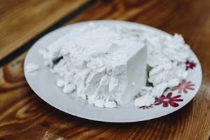 Feta cheese in a white plate on wooden background