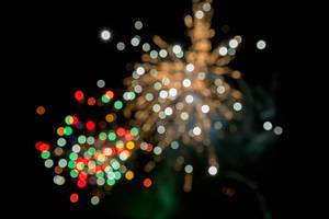 Feuerwerk zu Silvester mit weißen, roten und grünen Lichtern in Bokeh Effekt