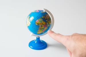 Finger pointing at a small globe indicating Africa