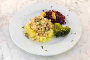 Fischkuchen auf Kartoffelbett, Broccoli und Rotkohl auf einem weißen Teller
