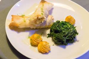 Fischröllchen mit Duchesse Kartoffeln und Spinat auf weißem Teller