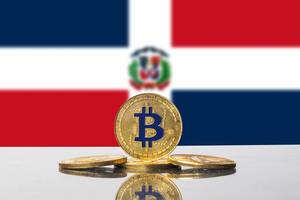 Flagge der Dominikanischen Republik mit Set aus vier goldenen Bitcoin-Münzen im Vordergrund