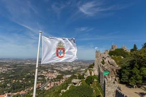 Flagge der Hofburg Castelo Dos Mouros mit den Burgmauern im Huntergrund
