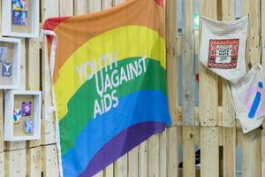 Flagge mit Regenbogenfarben und Aufschrift "Youth Against AIDS"