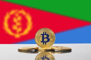 Flagge von Eritrea in Unschärfe mit Set aus vier goldenen Bitcoins im Vordergrund