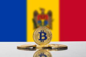 Flagge von Moldawien mit Unschärfe mit goldenen Bitcoin-Münzen im Vordergrund