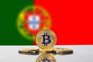 Flagge von Portugal mit Set aus vier goldenen Bitcoin-Münzen im Vordergrund