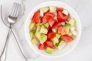 Flat lay above Avocado Tomato Onion and Cucumber Salad with forks
