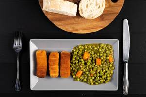 Flat lay above Fried Chicken Sticks with cooked Peas
