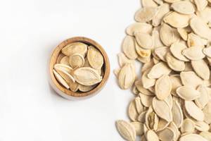 Flat lay above isolated pumpkin seeds above white background