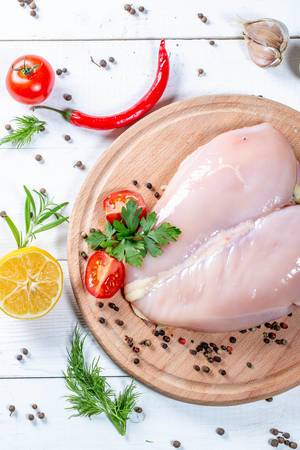 Flat lay composition with raw chicken breasts and ingredients on wooden background
