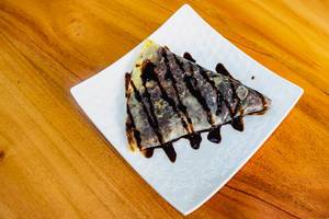 Flat lay of chocolate filled crepe on wooden surface