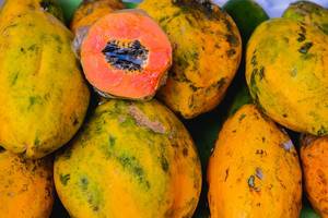 Flat lay of sliced papaya on top of other papayas (Flip 2019)