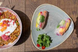 Flatlay of the vegetarian Fried Sunrice meal and two vegan Rainbow Summer Rolls in the coa Wok & Bowls restaurant in Cologne