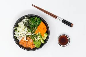 Flatlay: salmon Poke Bowl with avocado, chopsticks and soya sauce on white background