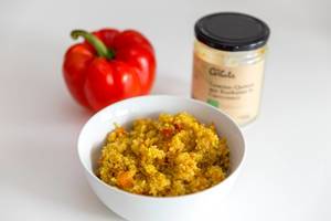Fleischfreie Ernährung: "Gemüse-Quinoa mit Kurkuma in Currysauce" von Carlota, in einer weißen Schüssel neben einer roten Paprika