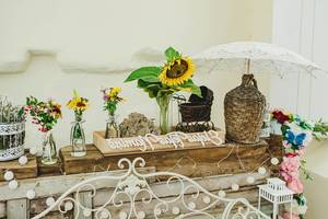 Florale Hochzeitsdekoration auf einem rustikalen Holzregal, mit Sonnenblumen in Vasen
