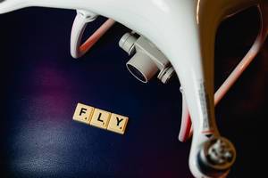 Fly word beside drone on blue surface