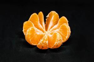 Food art: peeled and split orange with black background