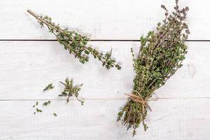 Food background of herb thyme on white kitchen table from above