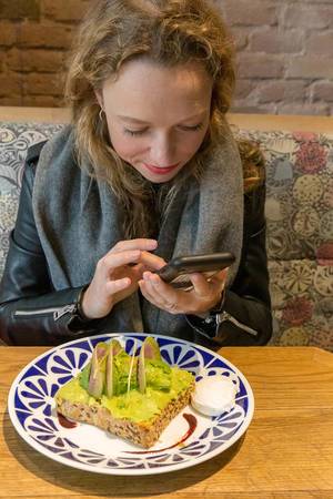 Food Bloggerin fotografiert ihr Avo-Toast aus Vollkorn mit Avocado, Yuzu Soße, Acai Soße, Pistazien und pochiertem Ei im Flax&Kale in Barcelona, Spanien
