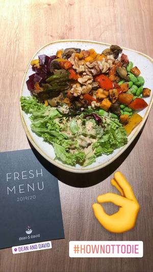 Foodbloger posts Instagram photo of healthy lunch "Veggie Buddha Bowl" by dean&david, next to their black fresh menu card