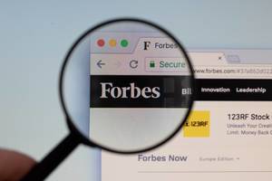 Forbes logo on a computer screen with a magnifying glass